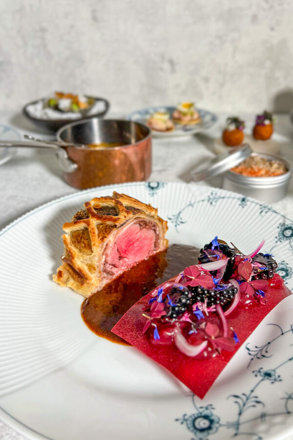 Duck wellington med andebryst, fjerkræsouffle og modnet skinke. Serveret med glaseret rødbede i kirsebær gastrik, syrlige rødløg, brombær og rød syre. Hertil køkkenchefens onde andesauce